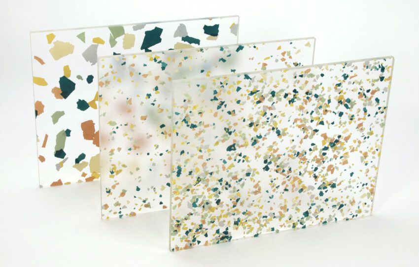 Three rectangular panels of translucent resin are arranged in a staggered formation against a blank background. Each of the resin panels is embedded with multicolored material pieces. The front two panels feature small color pieces, and the pattern in the front panel is more dense than the one behind it. The third panel at the back of the formation features large pieces of color.