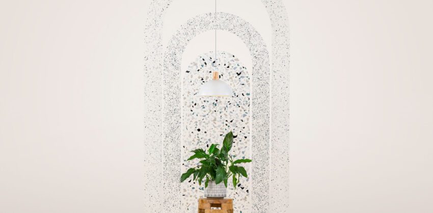 Three resin arches are arranged concentrically in front of a blank, neutral background. Each arch features a different terrazzo-like pattern. A white light hangs in the midst of the arches, and a house plant sits on a small wooden table in front.